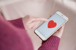 A single girl looking for love by tapping a love heart on her mobile touchscreen online dating app