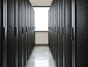 Storage racks aligned in a computer server room with a large window in the background.
