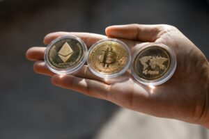Young man holding Crypto tokens Bitcoin, Ethereum, Ripple on palm of hand