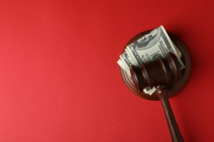 Judge gavel with dollars on red background