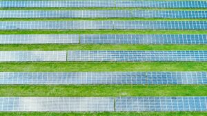 Equal lines of solar panels in the green field. Top view of solar power station for generation green