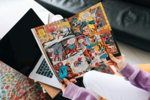 Person reading comic book at home in living room.