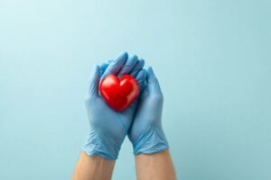 Heart disease prevention concept. Top view photograph of hands in medical gloves holding