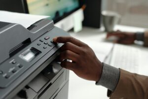 Hand of young African American man pressing button on panel of xerox